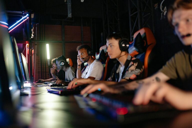 A group of young adults engaged in a focused PC gaming session indoors.